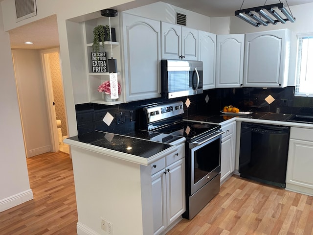 kitchen with appliances with stainless steel finishes, light hardwood / wood-style floors, white cabinets, and hanging light fixtures