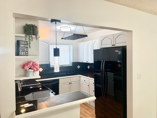 kitchen with decorative light fixtures, tasteful backsplash, black appliances, and white cabinets