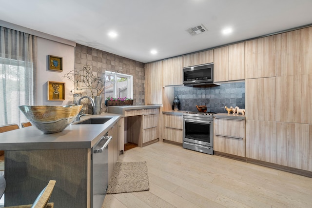 kitchen with light brown cabinets, light hardwood / wood-style flooring, stainless steel appliances, backsplash, and sink