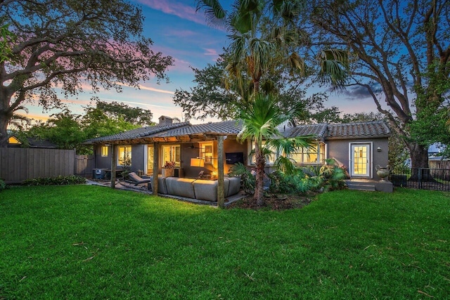 back house at dusk featuring a yard