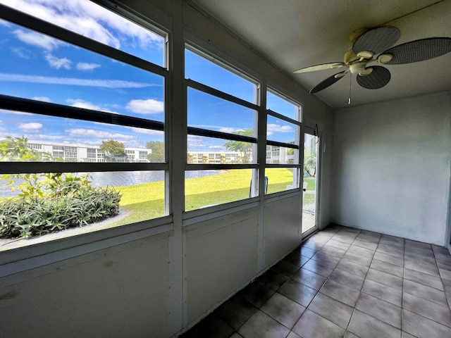 unfurnished sunroom with ceiling fan and a water view