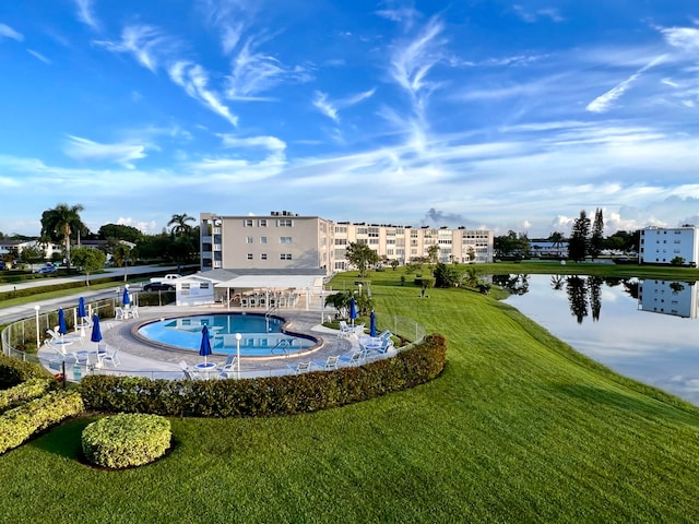 view of pool with a water view and a lawn