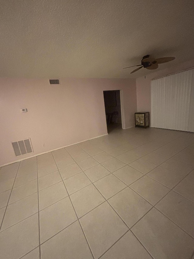 spare room with a textured ceiling, ceiling fan, and light tile patterned flooring