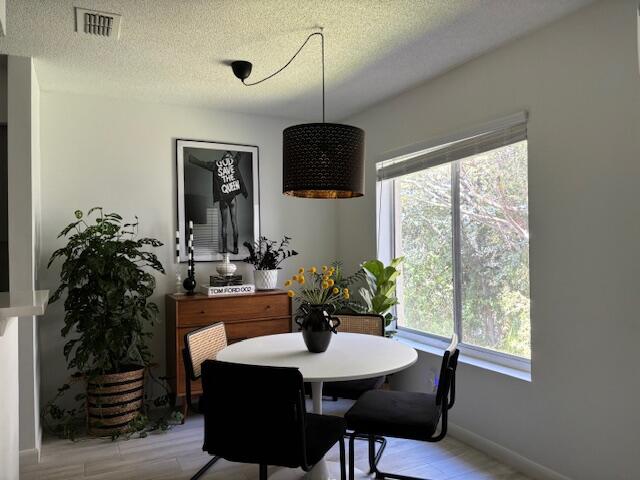 dining area with a textured ceiling and light wood-type flooring