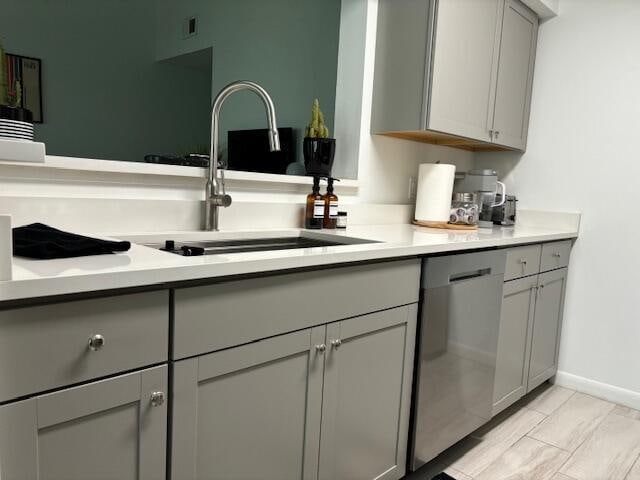 kitchen featuring gray cabinets, sink, and stainless steel dishwasher