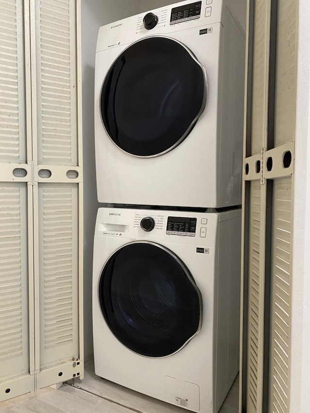 clothes washing area with light wood-type flooring and stacked washer and dryer