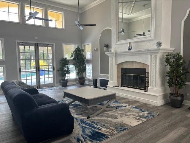 living room featuring ceiling fan, plenty of natural light, wood-type flooring, and a towering ceiling