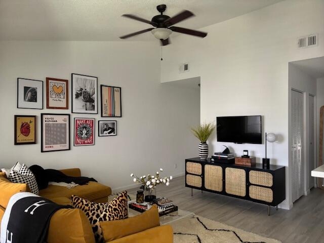 living room with high vaulted ceiling, ceiling fan, and hardwood / wood-style flooring