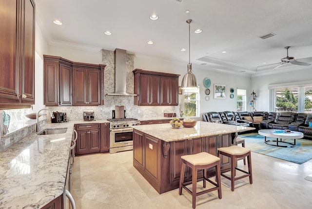 kitchen with a center island, high end stainless steel range, wall chimney exhaust hood, decorative light fixtures, and a kitchen bar