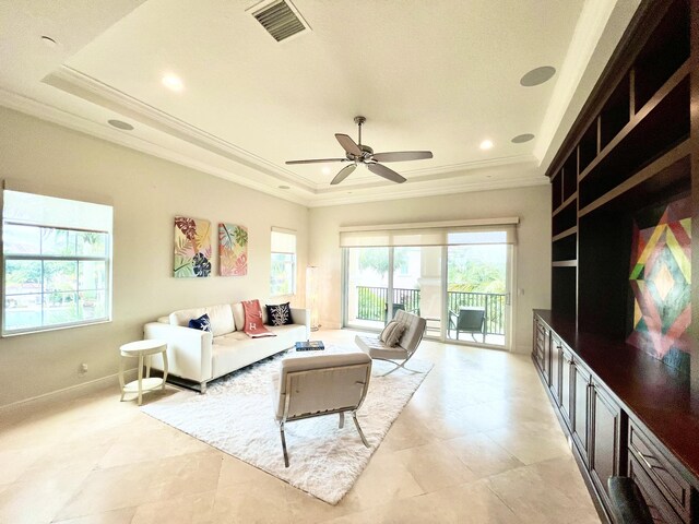 bedroom featuring access to exterior, a tray ceiling, multiple windows, and ceiling fan