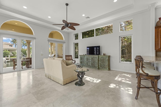 living room with ceiling fan, french doors, a tray ceiling, and ornamental molding