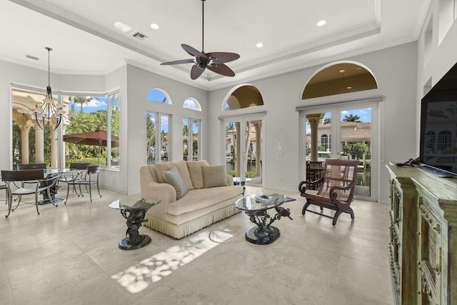 living room featuring french doors, a towering ceiling, a tray ceiling, crown molding, and ceiling fan with notable chandelier