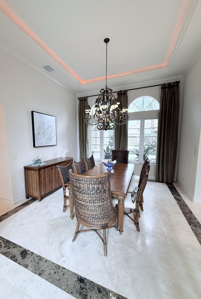 dining space featuring a tray ceiling, a chandelier, and crown molding