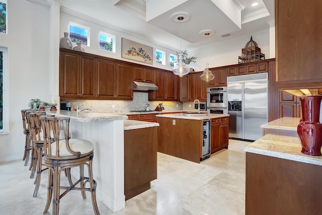 kitchen with an island with sink, kitchen peninsula, hanging light fixtures, appliances with stainless steel finishes, and beverage cooler