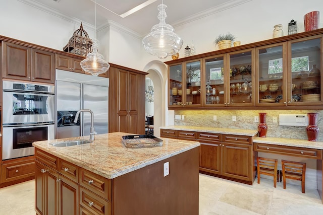 kitchen with appliances with stainless steel finishes, tasteful backsplash, hanging light fixtures, an island with sink, and sink