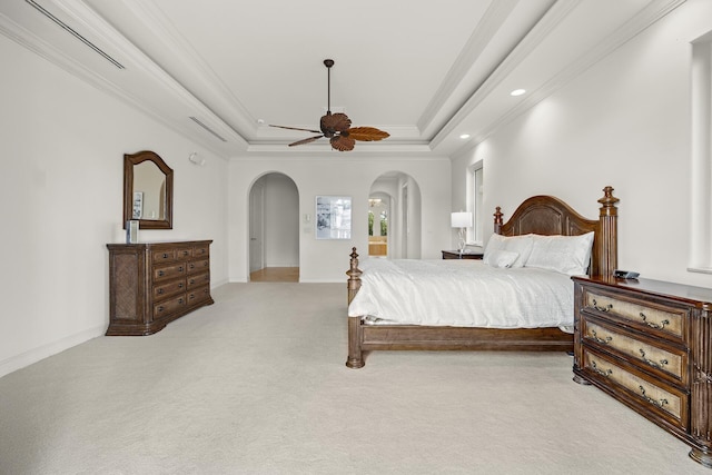 bedroom featuring a tray ceiling, light carpet, crown molding, and ceiling fan