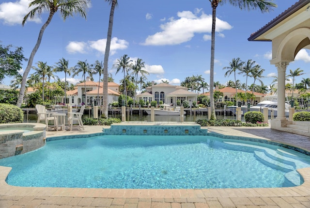 view of pool with a patio, a water view, and an in ground hot tub