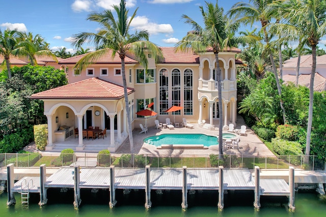 rear view of property featuring a water view, a balcony, a fenced in pool, and a patio area