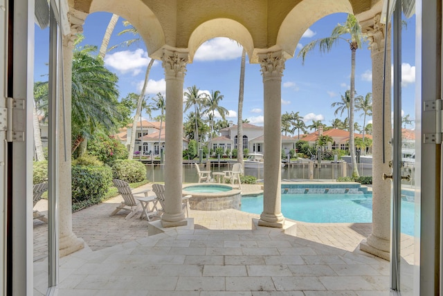 view of swimming pool with an in ground hot tub, a water view, and a patio