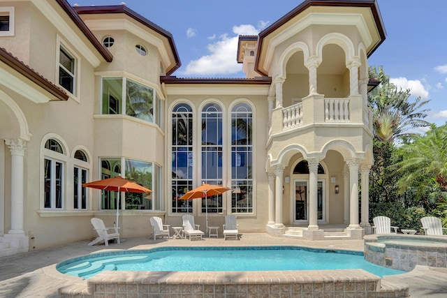 back of house with a pool with hot tub, a patio, and a balcony