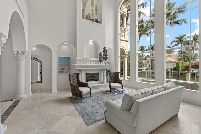 living room featuring a healthy amount of sunlight, ornate columns, and a fireplace