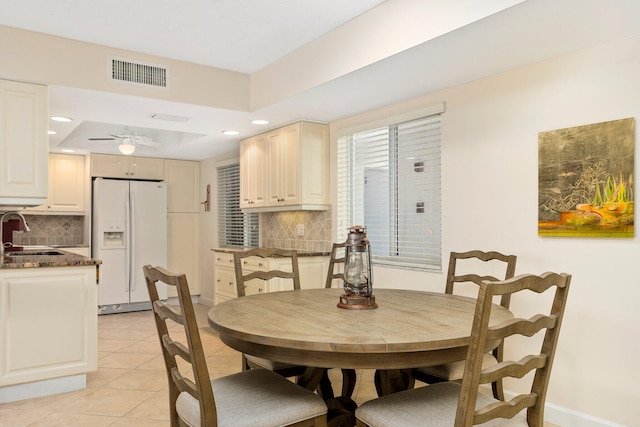 tiled dining area featuring ceiling fan, sink, and a tray ceiling