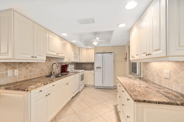 kitchen with light tile floors, dark stone countertops, ceiling fan, white appliances, and tasteful backsplash