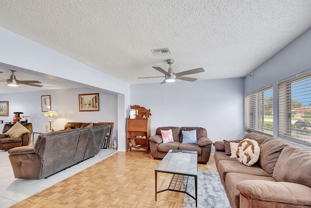 living room featuring ceiling fan, a textured ceiling, and light parquet floors