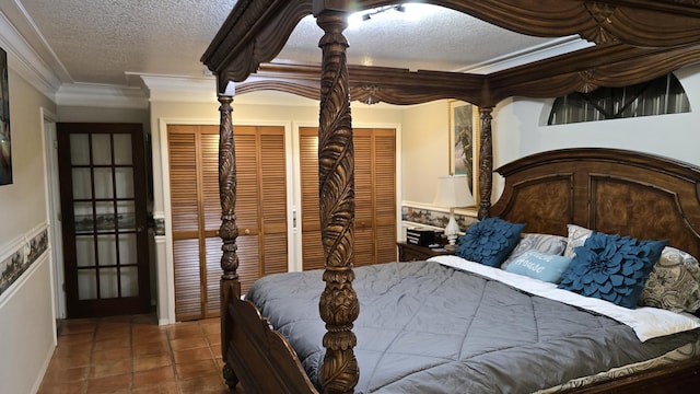 bedroom with tile patterned flooring, a textured ceiling, two closets, and ornamental molding