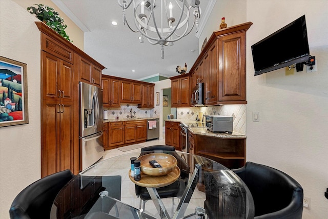 kitchen featuring tasteful backsplash, an inviting chandelier, ornamental molding, stainless steel appliances, and a sink