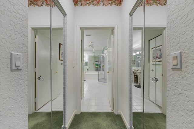 hallway featuring carpet flooring, tile patterned flooring, and a textured wall
