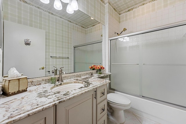 bathroom with combined bath / shower with glass door, vanity, wallpapered walls, and toilet