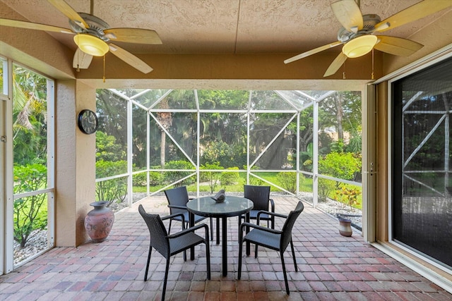 sunroom / solarium with outdoor dining area and ceiling fan