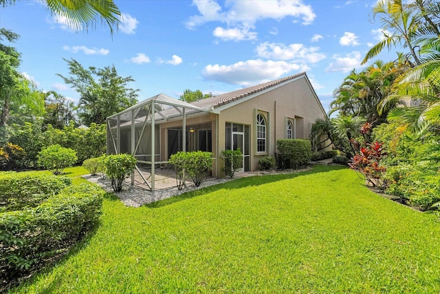 back of house featuring a patio area, stucco siding, a lanai, and a lawn