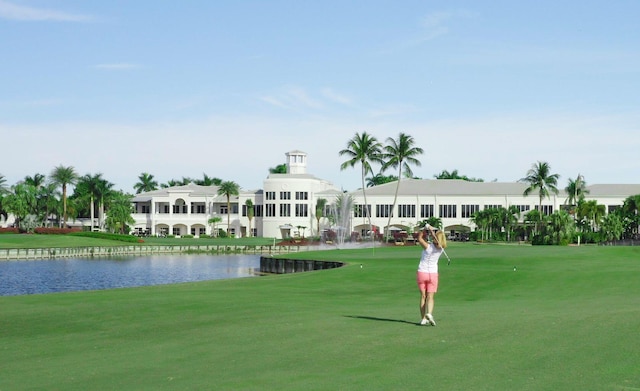 view of home's community with a water view, a lawn, and view of golf course
