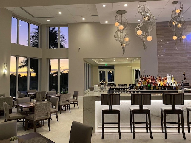interior space with a towering ceiling, a community bar, and recessed lighting