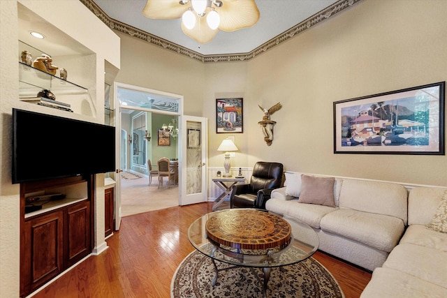 living room featuring wood finished floors, ornamental molding, and ceiling fan