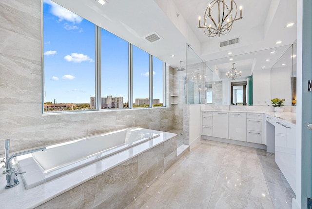 bathroom with a wealth of natural light, vanity, shower with separate bathtub, and a notable chandelier