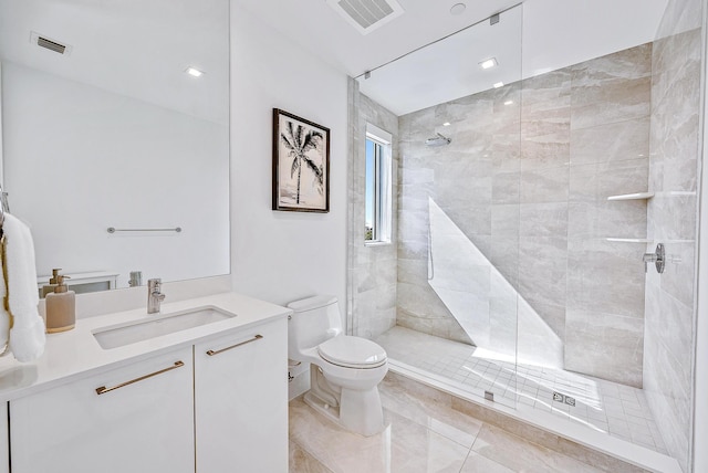 bathroom with vanity, tiled shower, and toilet