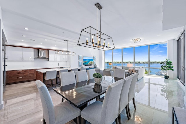 dining room with light tile patterned flooring, a water view, sink, and floor to ceiling windows