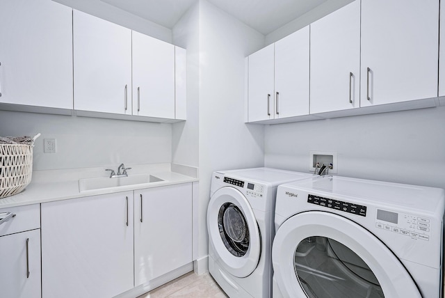 clothes washing area with light tile patterned flooring, washer and dryer, sink, and cabinets