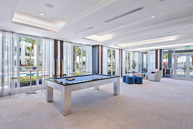 game room featuring french doors, a tray ceiling, billiards, and floor to ceiling windows