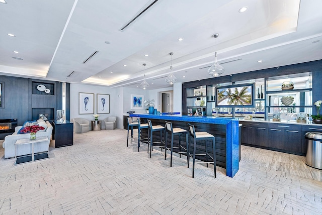 bar with a large fireplace, pendant lighting, and a raised ceiling