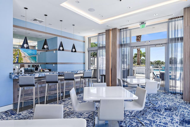 dining space featuring a tray ceiling, french doors, and a towering ceiling