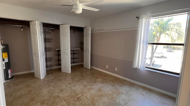 unfurnished bedroom with multiple closets, gas water heater, and ceiling fan