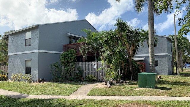 view of front of house with a balcony and a front lawn