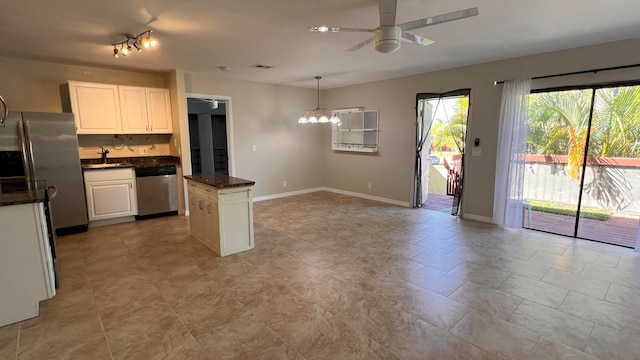 kitchen with sink, a kitchen island, stainless steel appliances, pendant lighting, and white cabinets