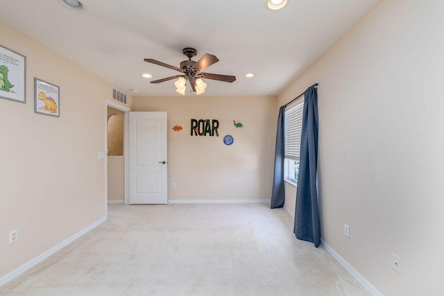 spare room with light colored carpet and ceiling fan