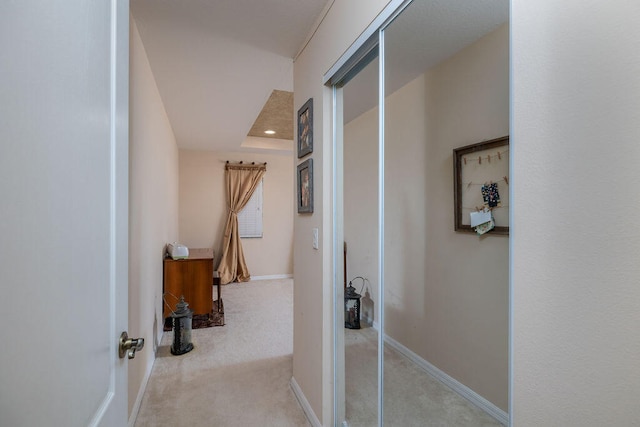 hallway with light carpet and a raised ceiling