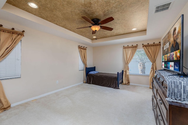 carpeted bedroom featuring ceiling fan and a tray ceiling